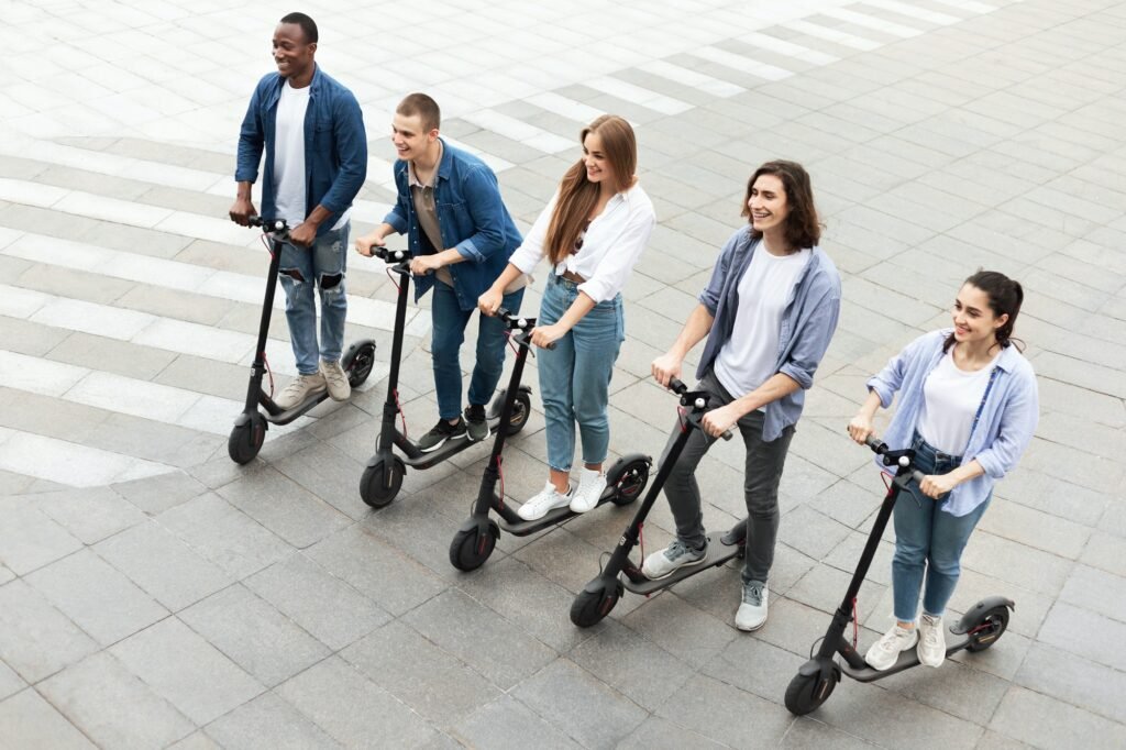 Five friends having ride on electric kick scooters