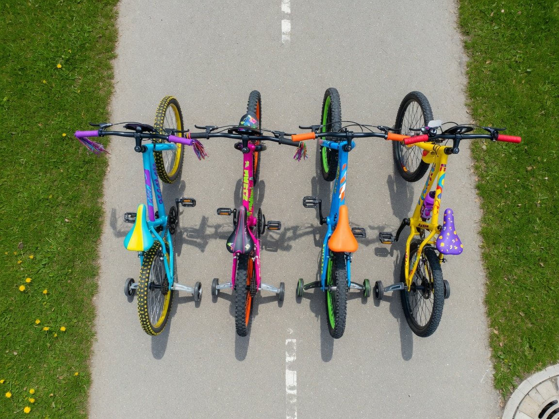 Close-up of a kids' mountain bike handlebar assembly — disc brake lever, gear shifter, and knobby grips — sharp product